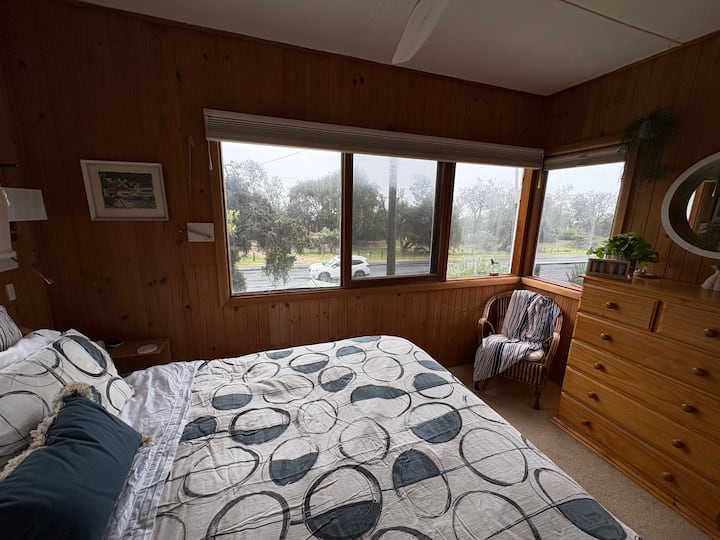 Cama tamaño king con mesitas y cajones. Ventanas con vistas a la playa. Acceso a la terraza a través de la puerta exterior.  El acceso a la sala de estar es a través del segundo dormitorio.