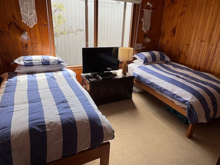 Dos camas individuales, ventilador de techo y TV.  Acceso desde el dormitorio 1 desde la puerta del granero.