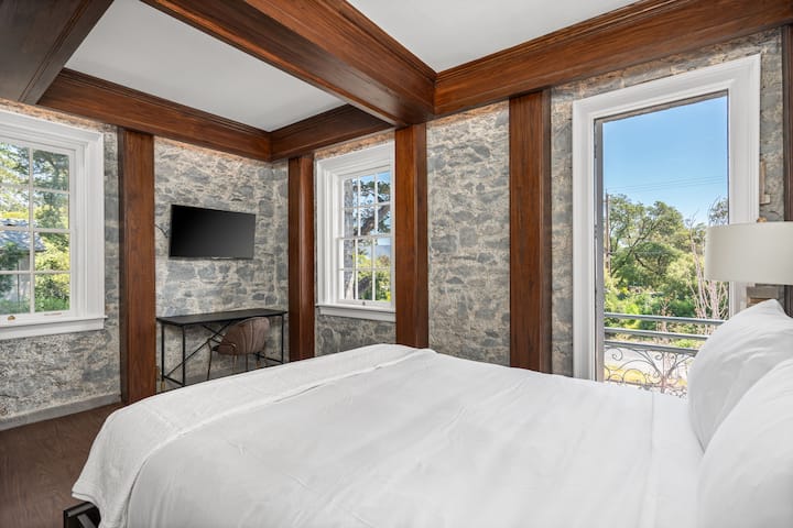 This is the private room you will be renting featuring warm wood-beam ceilings, stone-accented walls, and a cozy bed.