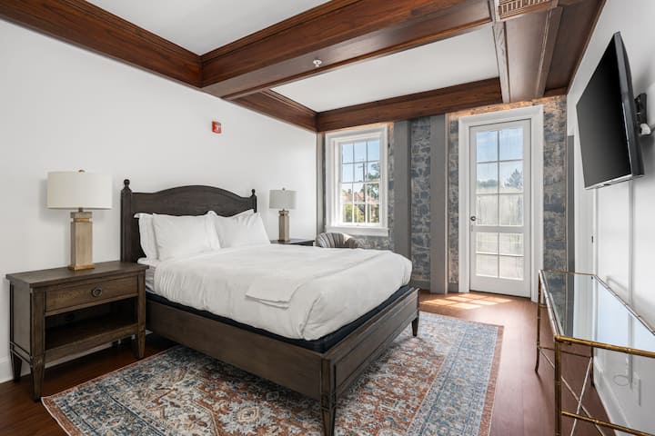 This is the private room you will be renting showcasing warm wood details, a cozy bed, and direct access to the outdoor balcony doors.