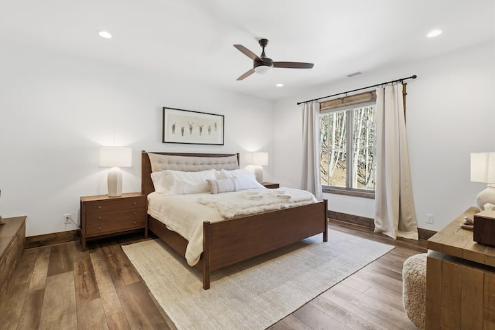 Settle into this peaceful bedroom where soft linens, natural light, and warm wood details create instant relaxation. Large windows frame forest views, making it the perfect place to unwind, read, and recharge.