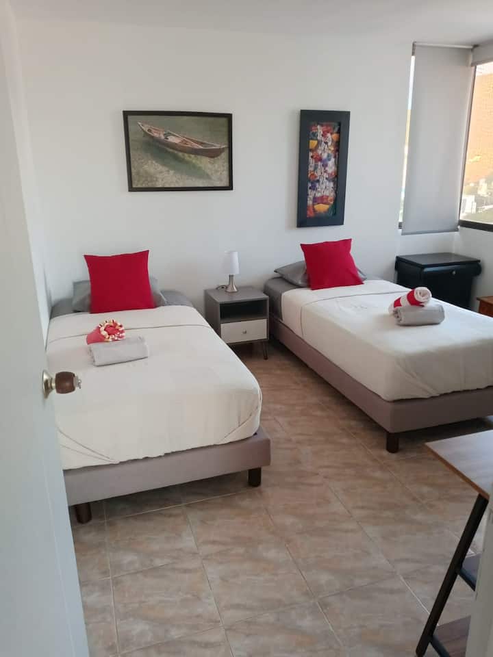 الغرفة 2: مفروشة بسريرين مفردين وطاولات ليلية ومكتب مع كرسي متحرك.