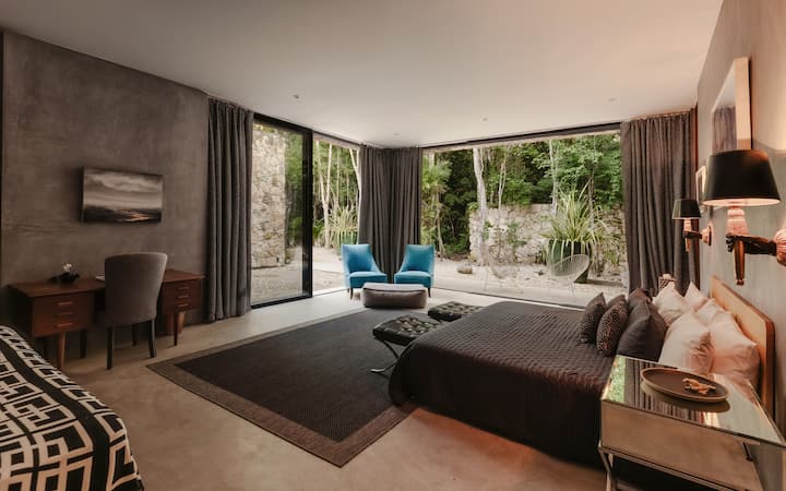 The spacious second master suite offers a king bed, a writing desk and large doors that open to the jungle and patio, creating a seamless connection to the outdoors.
