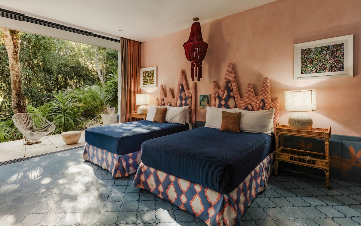 The fabulous fifth bedroom offers two double beds and a serene jungle patio, with colors that invite both playful warmth and calming energy, creating a space that feels joyful and deeply peaceful at once.
