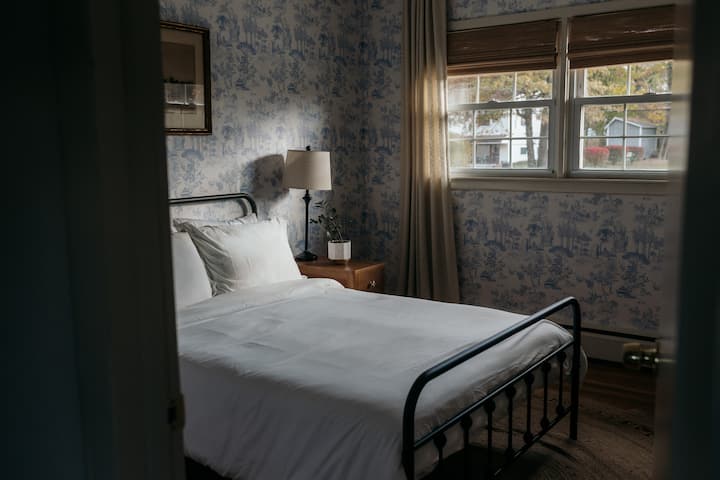 Una habitación luminosa y tranquila con papel tapiz de baño y detalles vintage curados.