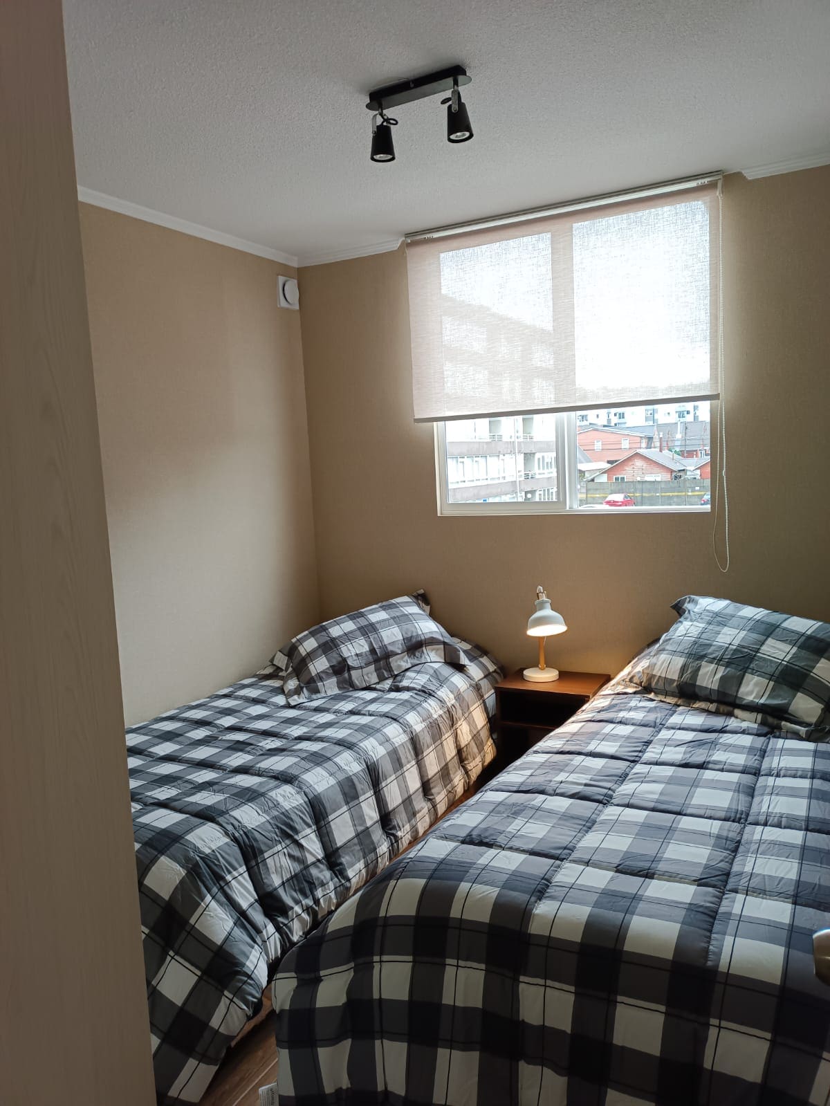 Dormitorio 2 camas con closet , valadof compartido y lámpara . 
