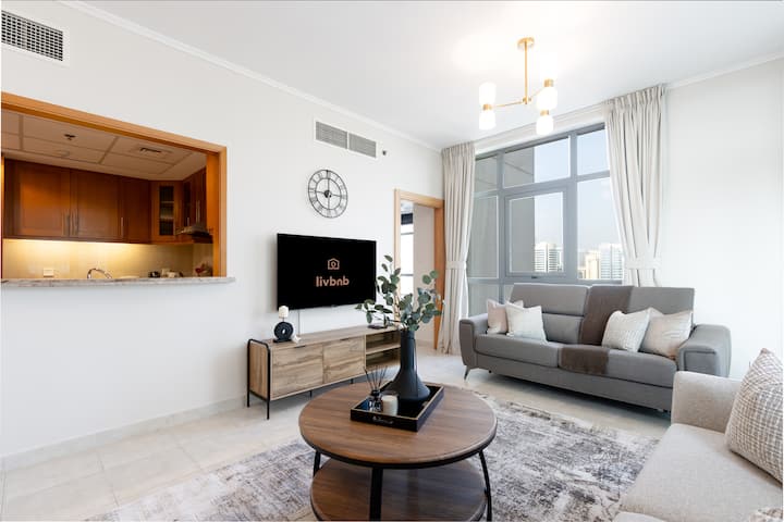 Светла всекидневна със смарт телевизор, неутрален декор и стилна масичка за кафе.