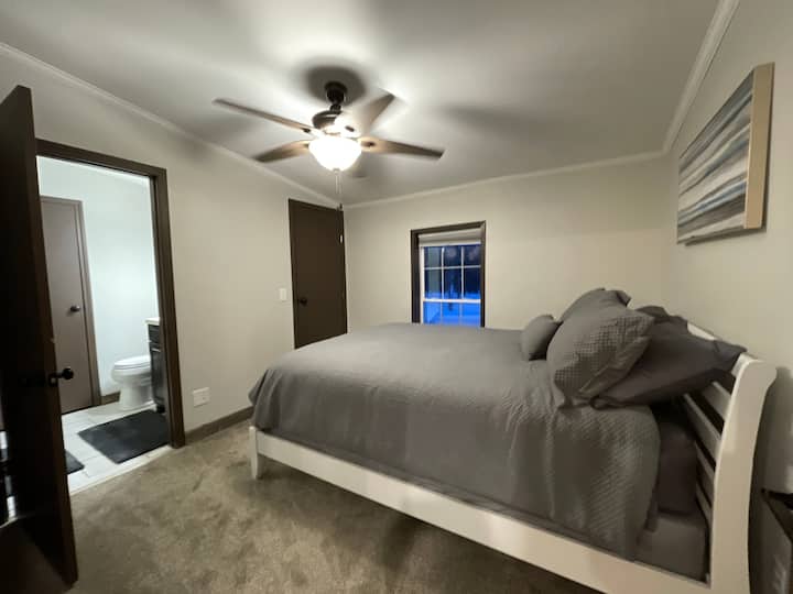 חדר שינה לאורחים עם מיטת קווין סייז וחדר רחצה מלא משותף עם חדר השינה הבא.