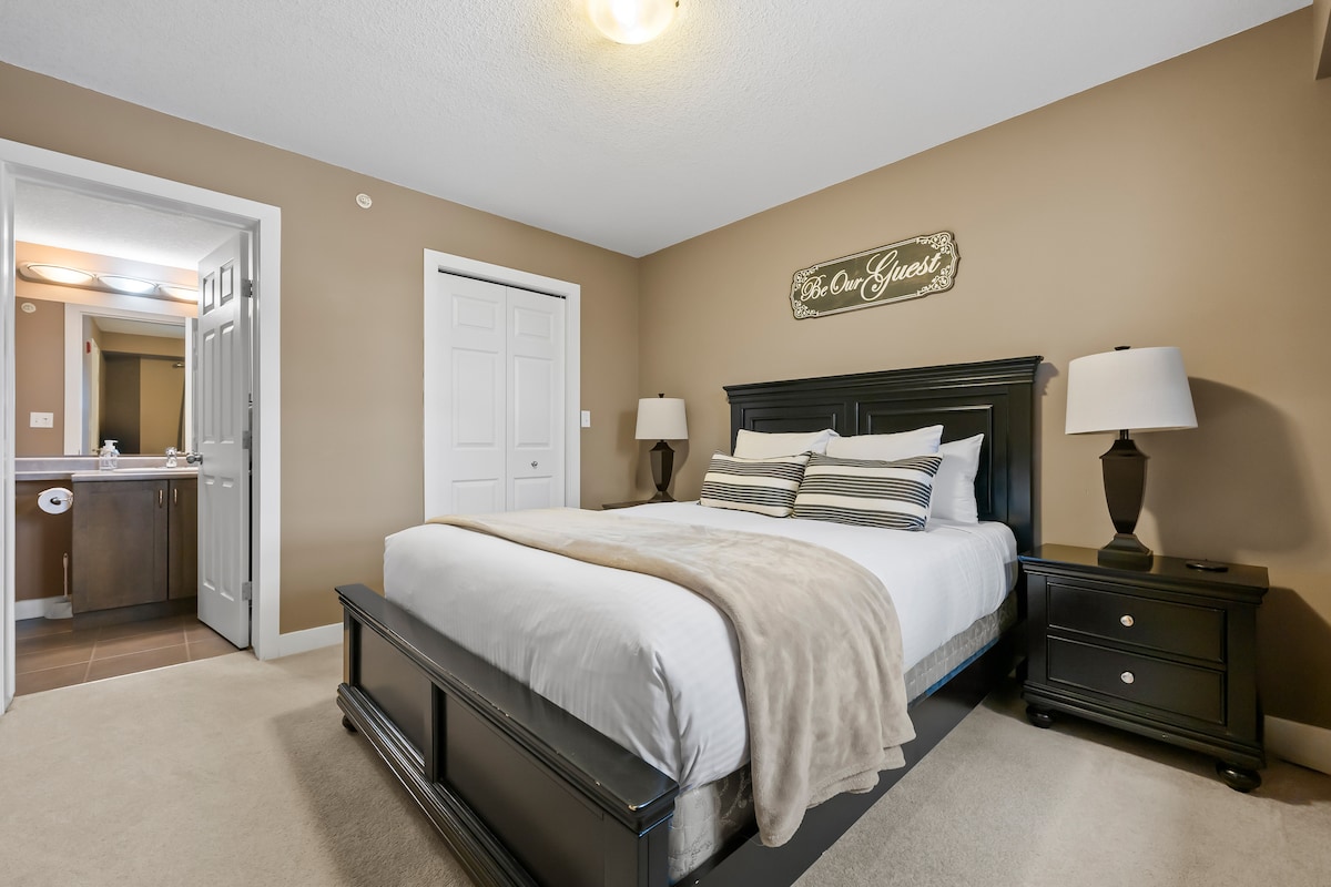Chambre principale avec un lit queen, une commode, un dressing et une salle de bains privée.
