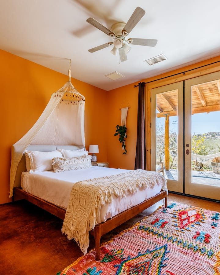 Bright, inviting queen room featuring soft ivory linens and outdoor access.