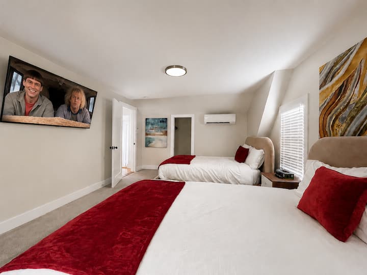 Spacious bedroom with two full beds, TV and air conditioning.