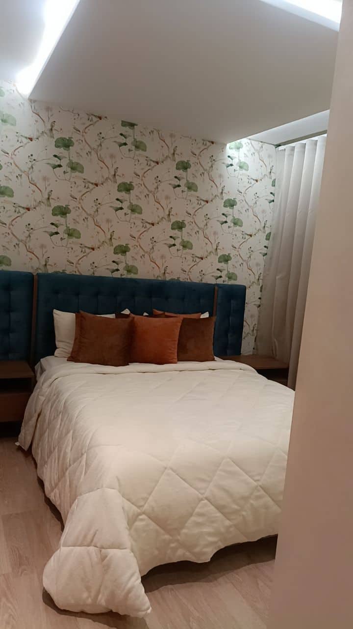 Chambre principale avec grand lit, mobilier raffiné, balcon et salle de bain privée.