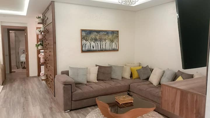 Deuxième salon avec canapé moderne et touches décoratives marocaines.