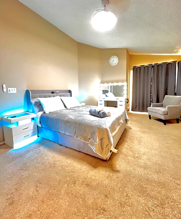 Karibu kwenye chumba chako kikuu cha kulala, kilicho na mwanga wa kutosha. Furahia televisheni janja ya inchi 65 iliyo kando ya eneo la kukaa lenye starehe, bora kwa ajili ya kupumzika.