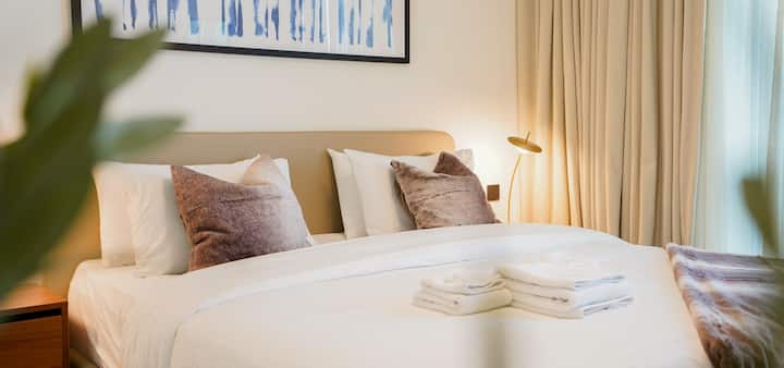 חדר שינה שקט עם מיטת קינג סייז, מצעים יוקרתיים ועיצוב מרגיע בהשראת חוף הים. חלונות גדולים משפרים את תחושת האוורור, ומציעים מפלט שקט המיועד ללילות שלוים ולבוקרים רגועים.