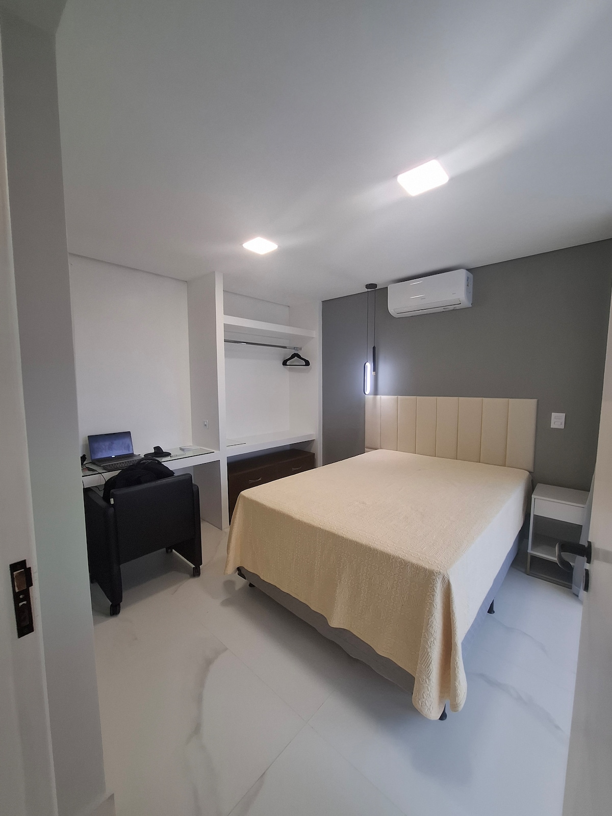 Dormitorio con aire acondicionado, armario, cajón y espacio de trabajo.