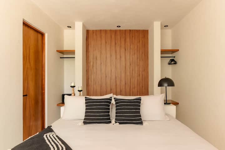 The second bedroom offers a comfortable king bed and serene jungle garden views, creating a peaceful retreat surrounded by lush greenery and natural light.
