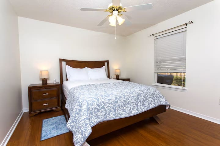 Cette chambre à coucher offre un lit queen size et est l'une des deux chambres situées dans le couloir à côté du salon.  Station de recharge et lampes de chaque côté du lit.