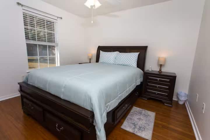 Cette chambre à coucher avec grand lit est séparée des autres chambres à coucher, avec une salle de bain dans le couloir. La chambre donne sur la piscine et la belle cour arrière. Le hall a une porte qui mène directement à la salle Florida. Station de recharge et lampes de chaque côté du lit.