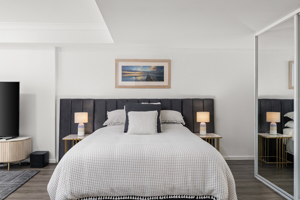 საწოლი (queen‑size), რომელსაც ახალი მატრასი და ახალი თეთრეული აქვს, გარშემო დგას მარმარილოს მაგიდები და თანამედროვე ლამპები. საცხოვრებელს კიდევ უფრო განსაკუთრებულს ხდიან კენ დანკანის მიერ გადაღებული ტბის ფოტოები, რომლებიც ლონგ‑ჯეტის ხედებით გამორჩეულ ადგილასაა გადაღებული.