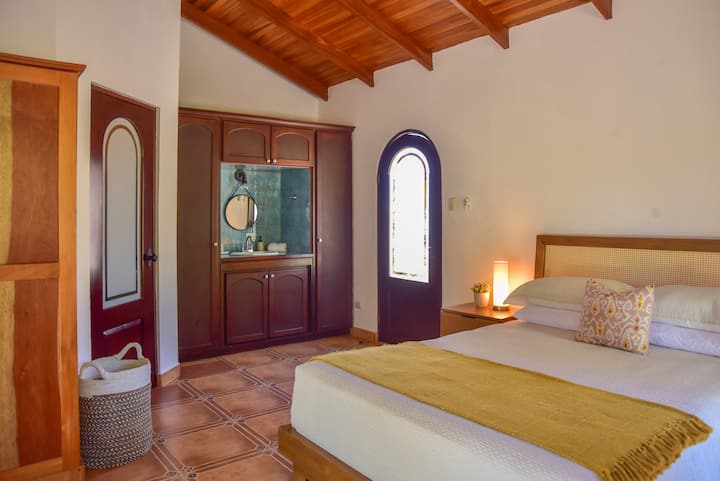 This private bedroom offers a Queen size bed with a beautiful design and soothing linens for a perfect nights rest. It has a full bathroom and offers direct access to the outdoor courtyard.  