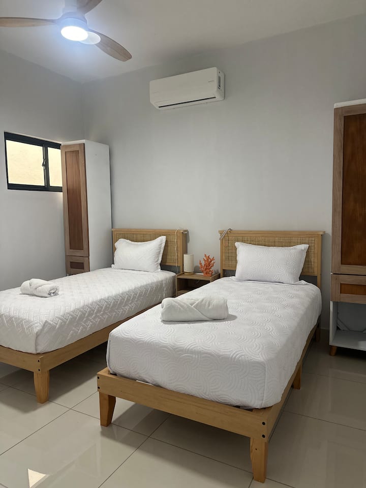 Chambre à deux lits avec des lits propres et confortables et des draps doux, idéale pour des amis ou de la famille qui partagent la chambre. Un espace lumineux et sobre conçu pour un séjour reposant et détendu.