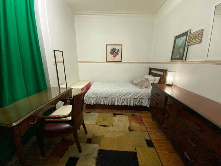 Alojamiento con cama individual, ropa de cama, tocador, espejos, ropero, mesa de trabajo. separa el pasillo y otra estancia  lienzos de tela, para mayor privacidad.