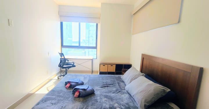 Recámara principal amplia y luminosa, equipada con cama cómoda, área de trabajo y ventanales que aportan excelente iluminación natural y un ambiente tranquilo.