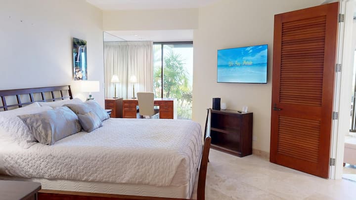 Suite principal con cama tamaño king, vistas al mar y espacio de trabajo privado