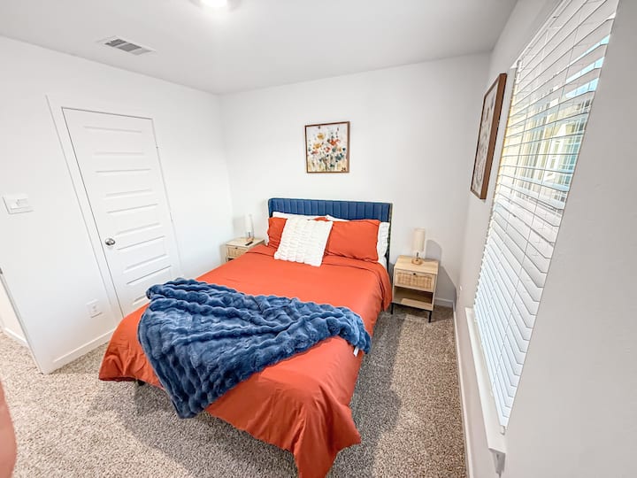 Bright secondary bedroom with a cozy bed, soft carpeting, and warm accents. Thoughtfully styled for comfort and relaxation, ideal for a restful night’s sleep.