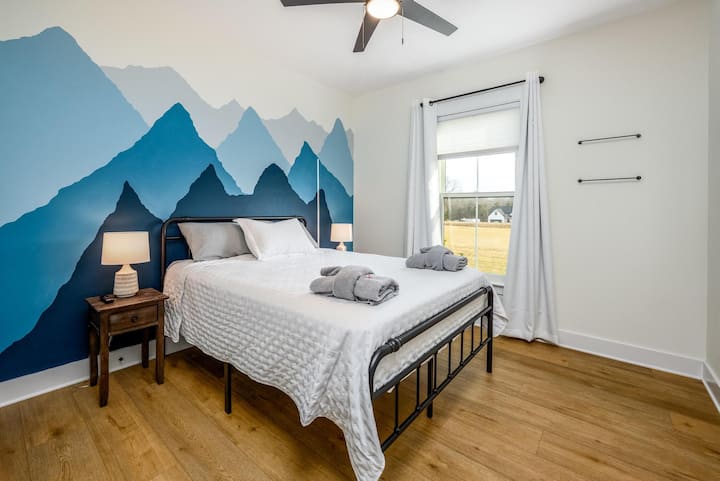 Dhomë miqsh me krevat dopio "queen". Dollapi ka rafte dhe sirtarë të integruar me hapësirë për varje.