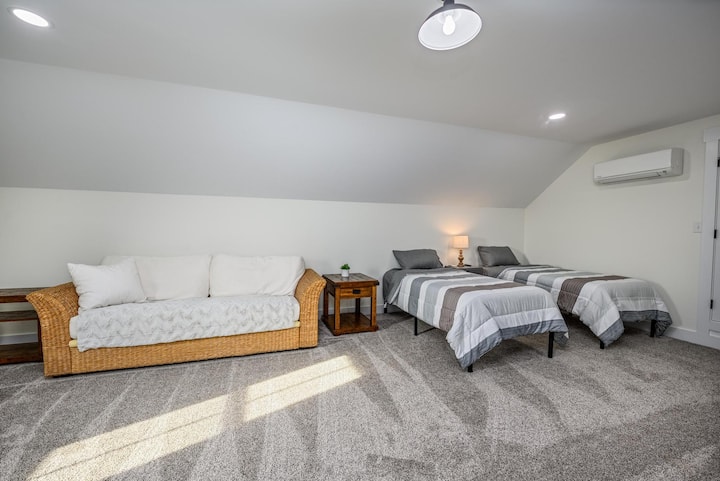 Loft në katin e sipërm me 2 krevate dopio, tavolinë me letra, televizor dhe divan. 