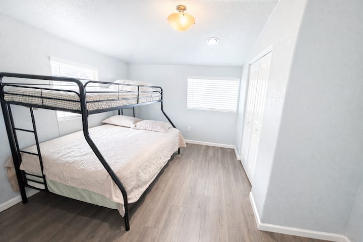 Dormitorio secundario con una litera con una cama tamaño queen en la parte inferior y una cama doble en la parte superior, con sábanas limpias y cómodas, ideal para niños o huéspedes adicionales.
