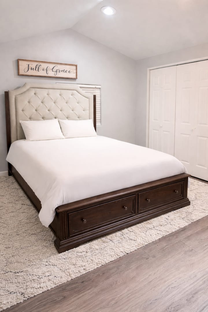 Dormitorio principal con una cómoda cama tamaño queen, sábanas frescas y almacenamiento incorporado, diseñado para una noche de sueño tranquila y reparadora.