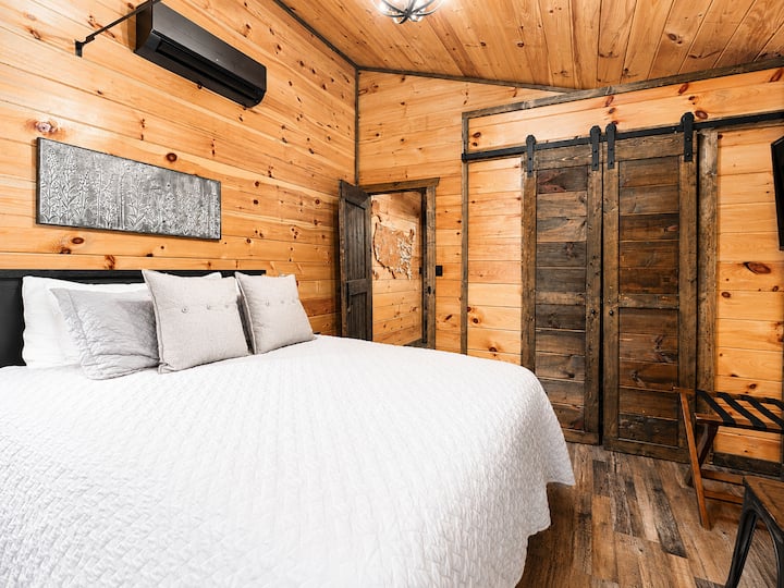 The private second bedroom features a comfortable Queen bed, striking wood paneling, and custom sliding barn doors to complete the Mountain Modern aesthetic.