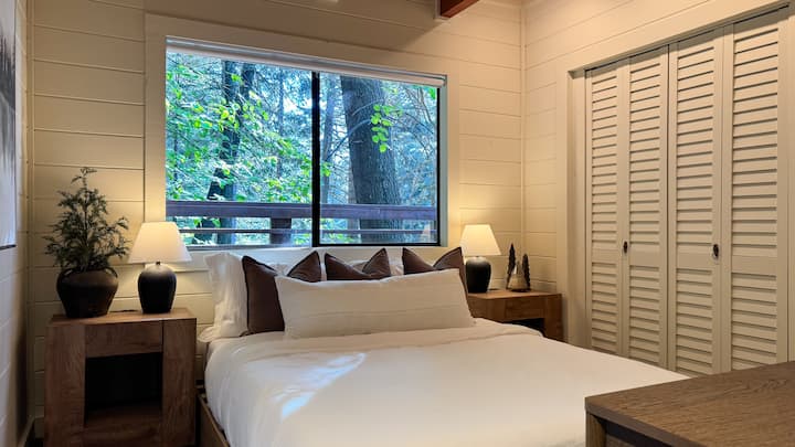 The main level bedroom has a Queen-size bed, serene forest views, and is located directly across from the full bathroom.