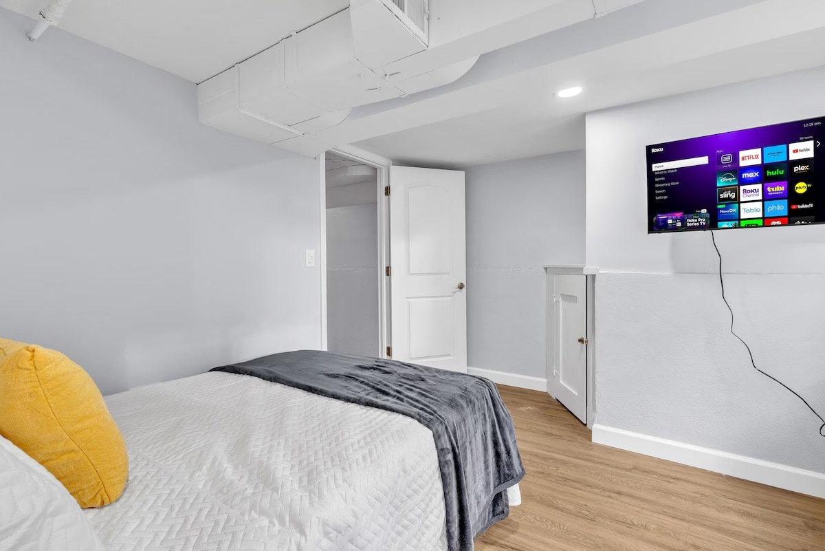 Lit queen-size avec tables de chevet, placard et télévision — arrangement de couchage confortable.