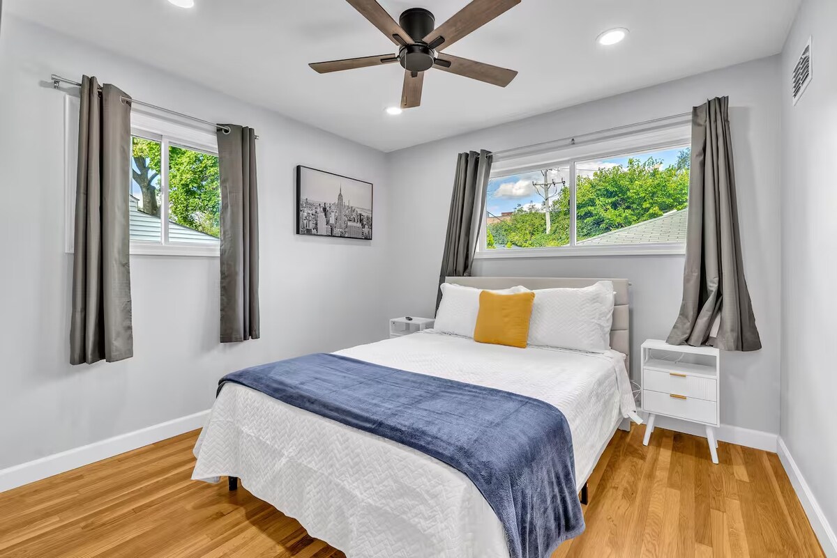 Un lit queen avec matelas mi-mou, commode, espace de rangement, ventilateur de plafond et télévision. 