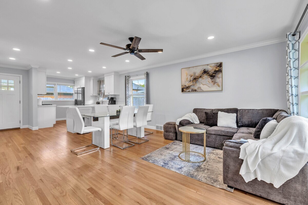 Espace de vie confortable avec des sièges confortables (canapé), une télévision et de la lumière provenant des fenêtres — idéal pour se détendre ou regarder des films.