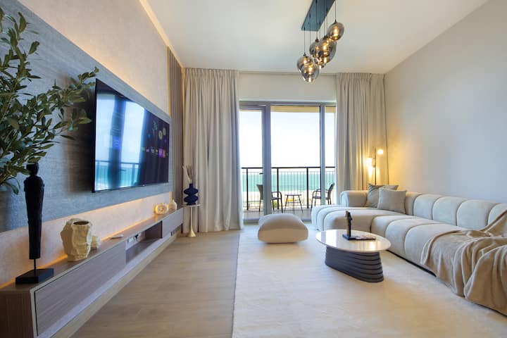 Opustite se u dnevnom boravku, prostranom prostoru s udobnim garniturom, televizorom i stolom u sredini koji pruža svakodnevnu udobnost. S prozorom okrenutim prema moru, idealan je za mirne večeri ili ležerna okupljanja tijekom vašeg boravka u Dubaiju.