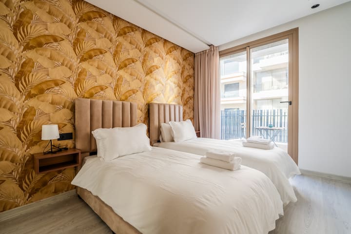 • Svetlá druhá spálňa s dvoma pohodlnými samostatnými posteľami (premeniteľné: dajú sa spojiť do jednej manželskej postele). Posteľná bielizeň v hotelovej kvalite, čalúnené čelá postelí, nočný stolík. Veľké okno/dvere na balkón, ideálne na vyvetranie izby a na fajčenie.