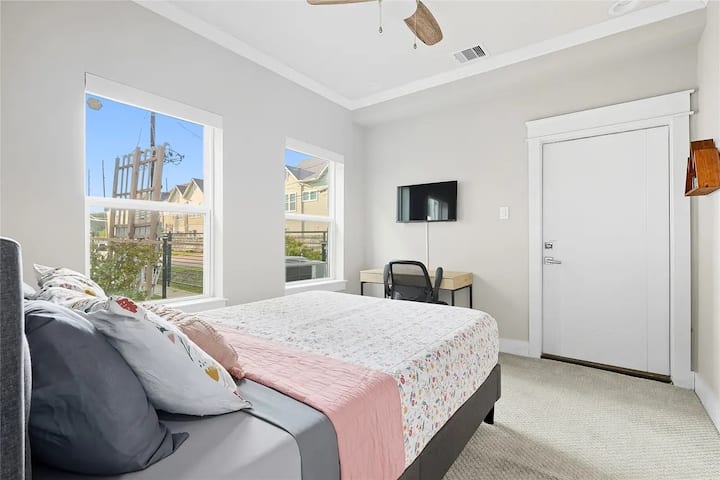 Comfortable bedroom featuring electric shades, a TV, and a private en-suite bathroom for added privacy and convenience.