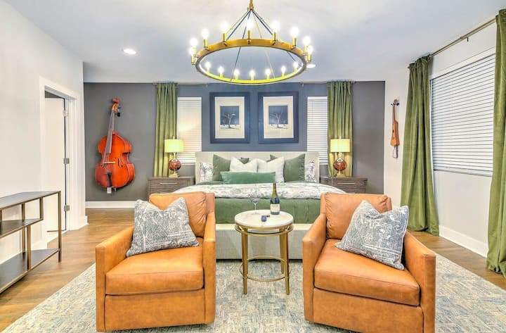 Spacious, stylish bedroom with plush bed, cozy seating area, smart TV, elegant lighting, and warm décor—perfect for relaxing in comfort after a day exploring the city.