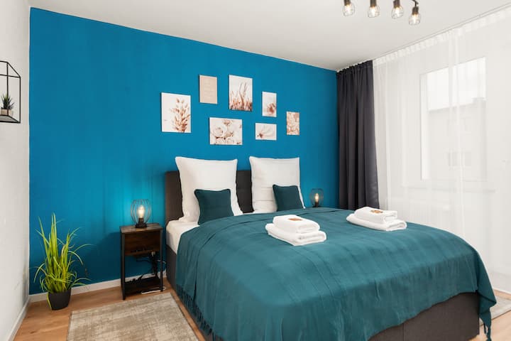 חדר שינה שקט עם ערכת צבעים הרמונית, פתרון מיטה זוגית נוח וריהוט טקסטיל איכותי.