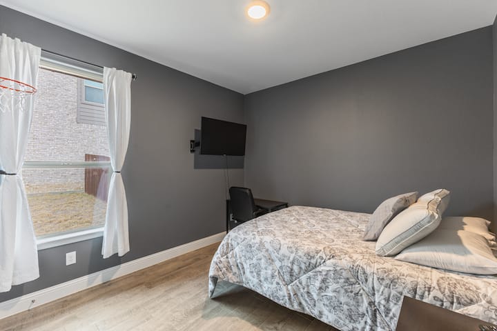 Chumba cha kulala chenye starehe kilichobuniwa kwa ajili ya kupumzika na kuwa na tija, chenye televisheni kwa ajili ya kupumzika na sehemu mahususi ya kufanyia kazi kwa ajili ya kuendelea kuwa makini.