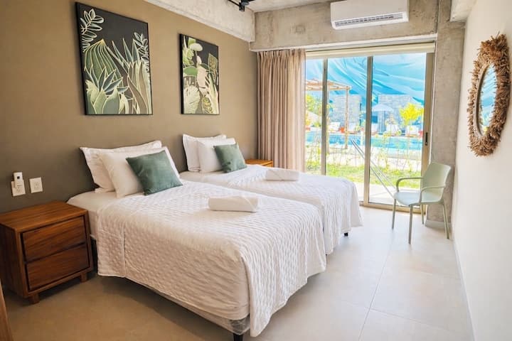 Dva luksuzna madraca za odvojene krevete s hotelskim kvalitetnim posteljinom i mekim jastucima. Kreveti se mogu spojiti u jedan veliki bračni krevet ili razdvojiti u dva zasebna kreveta. Klizna stijena vrata i klima-uređaj. Ormar nije prikazan na fotografiji.