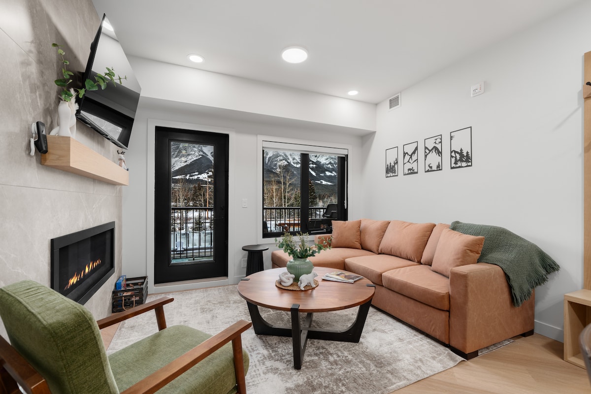 Útulná obývacia izba s kozubom, inteligentným televízorom a výhľadom na hory priamo z pohovky, ktorá sa dá rozložiť na posteľ pre ďalšie miesto na spanie
