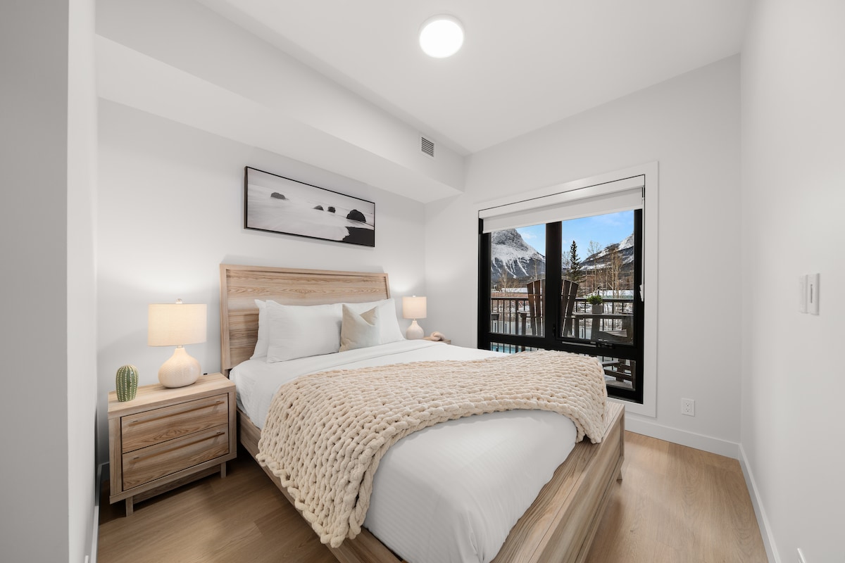 Svetlá, moderná spálňa č. 2 s manželskou posteľou, mäkkou posteľnou bielizňou, jemným osvetlením a oknom s výhľadom na hory.