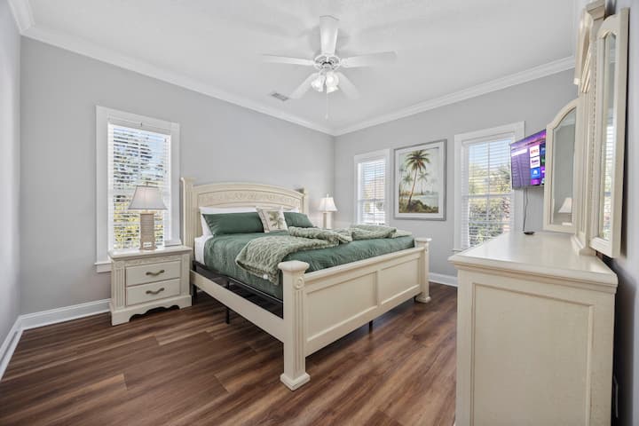 Spavaća soba s velikim bračnim krevetom i zelenim detaljima u primorskom stilu.  Pametni televizor. Pogled na bazen i dvorište.  Imajte na umu da svaka spavaća soba ima stanicu za punjenje na svakom noćnom ormariću (s AC, USB-A i USB-C priključcima)