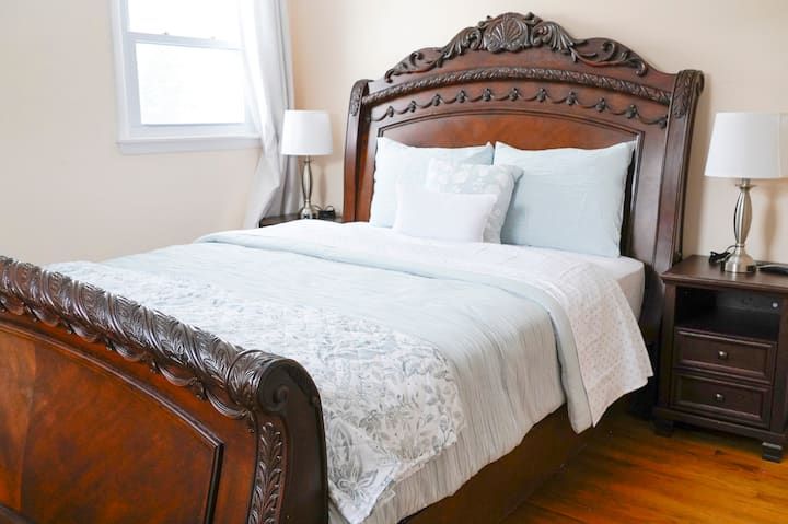 חדר שינה מקסים עם מסגרת מיטה עץ קלאסית ומזרן קווין סייז נוח.